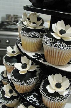 cupcakes decorated with black and white flowers are stacked on top of each other