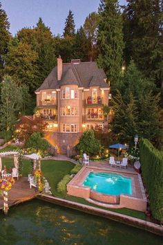 an aerial view of a large house with a pool in the foreground and landscaping around it