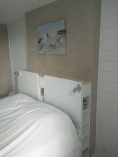 a white bed sitting in a bedroom next to a painting on the wall above it