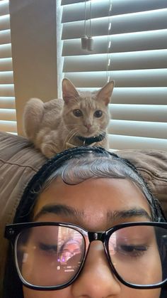 a cat sitting on top of a woman's head with her eyes wide open