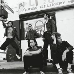 four young men sitting on the curb in front of a store