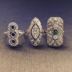 three diamond and emerald rings, one in white gold the other in silver with diamonds