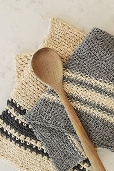 two crocheted dishcloths and a wooden spoon on a table