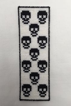 a white and black beaded wall hanging with skulls in the middle, on a white background