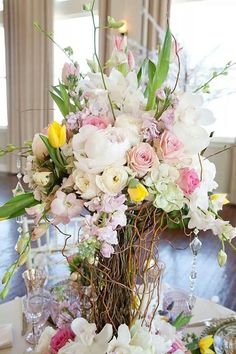 a vase filled with lots of flowers on top of a table next to plates and glasses