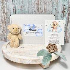 a teddy bear sitting on top of a wooden table next to a card and flower