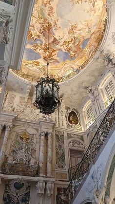 an ornately decorated ceiling and chandelier in a room with white walls, windows, and painted ceilings