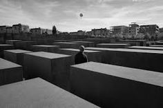 a man standing in the middle of a large group of concrete blocks with buildings in the background