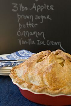 an apple pie sitting on top of a blue table cloth next to a chalkboard