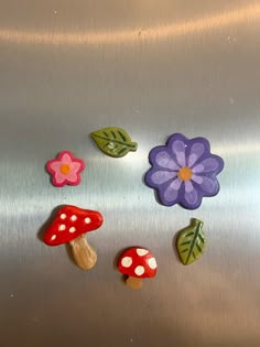 four different types of flowers and mushrooms on a metal surface in the shape of magnets