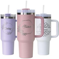 three different colored travel mugs with their names on the side and one has a straw in it