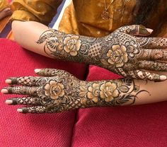 a woman's hands with hennap and flowers on her arms, both covered in tattoos