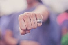 a person with a ring on their finger pointing at the camera while wearing a purple shirt