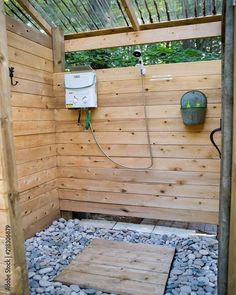 an outdoor shower with rocks and gravel in the ground next to a wooden fenced area