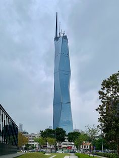 a very tall building sitting in the middle of a park next to a sidewalk and trees