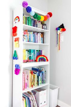 a bookshelf filled with lots of books next to a wall mounted rainbow decoration