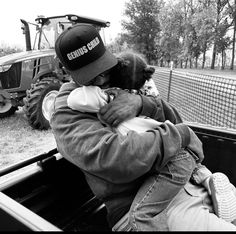 a man holding a baby in the back of a truck