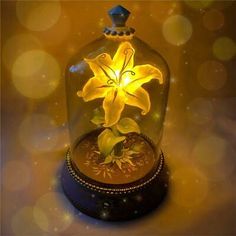 a yellow flower under a glass dome with lights on the top and below it is a gold plated clock