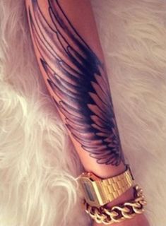 a woman's arm with tattoos and chains on her leg, in the shape of an angel wing