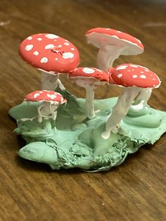 three red and white mushrooms sitting on top of a wooden table