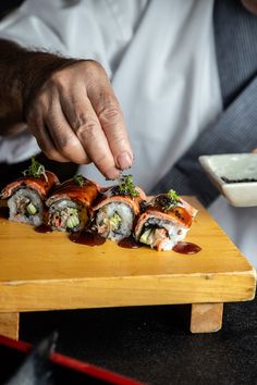 a man is cutting up sushi on a wooden board