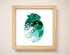 a framed art print of a green frog with leaves on it's back, in a wooden frame