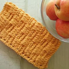 an orange crocheted dishcloth next to some apples