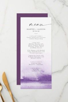 the purple watercolor wedding menu is displayed on a marble table with gold utensils