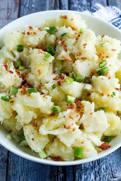 a white bowl filled with mashed potatoes and green onions