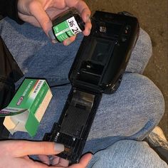 a person sitting on the ground holding a cell phone and batteries in their hands,