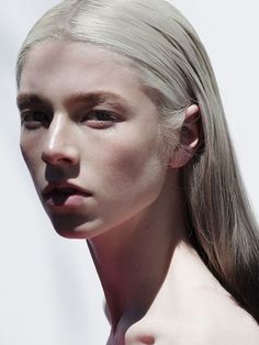 a woman with long blonde hair and no shirt is posing for the camera while wearing an earring