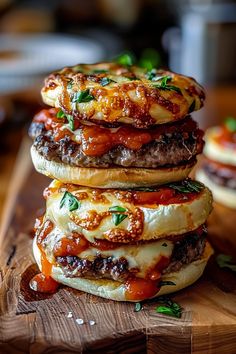 three burgers stacked on top of each other with sauce and cheese, sitting on a wooden cutting board