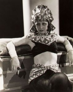 an old black and white photo of a woman in egyptian garb sitting on a trunk