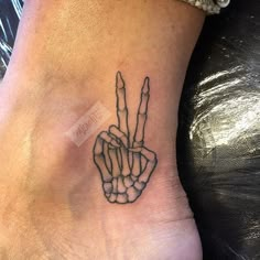 a small tattoo on the foot of a person with two fingers in the shape of a peace sign