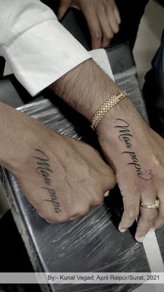 two people holding hands with tattoos on them