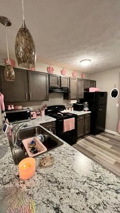 a kitchen with granite counter tops and black appliances in the center, along with pink decorations on the walls