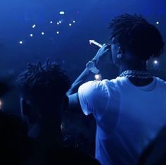 a man with dreadlocks on his head holding a microphone in front of a crowd