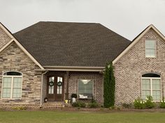 a large brick house with green grass and bushes