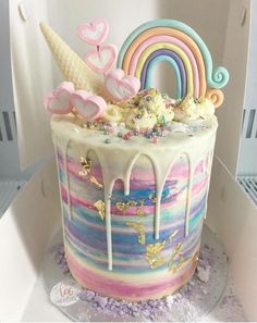 the cake is decorated with an ice cream rainbow and unicorns on it's icing