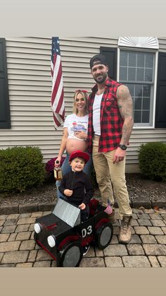 a man and woman standing next to a child in a toy car with an american flag on it