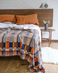 a bed with an orange and blue blanket on top of it next to a night stand