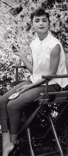 black and white photograph of woman sitting on chair with wine glass in hand, outdoors