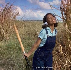 a woman in overalls holding a baseball bat next to tall grass and blue sky