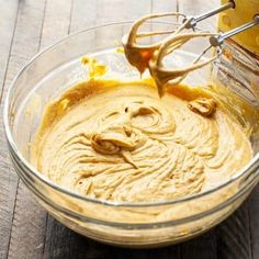 a glass bowl filled with batter on top of a wooden table