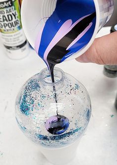 someone is pouring blue liquid into a clear glass vase with sprinkles on it