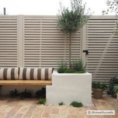 a bench sitting in the middle of a patio next to a wall with plants on it