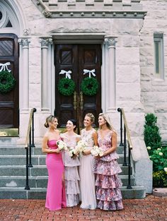 three bridesmaids standing in front of a church with their bouquets on the steps