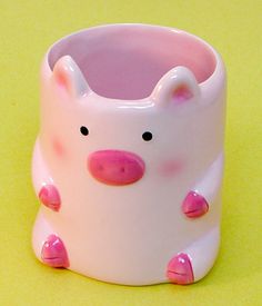 a pink and white pig cup sitting on top of a yellow table