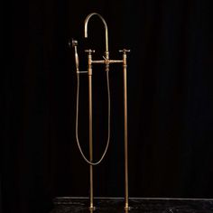 an antique brass shower head and handset on a marble countertop in front of a black background