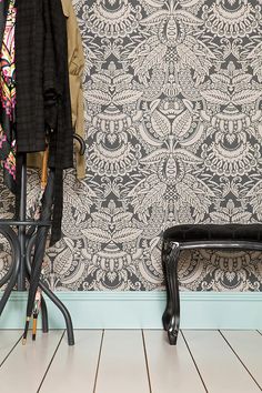 a coat rack sitting next to a black bench on top of a hard wood floor